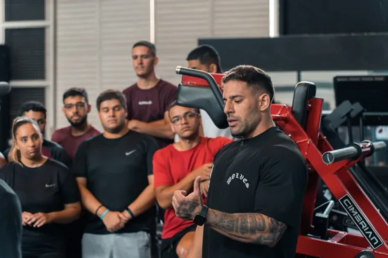 Gui Teixeira falando a um grupo de pessoas dentro de uma academia